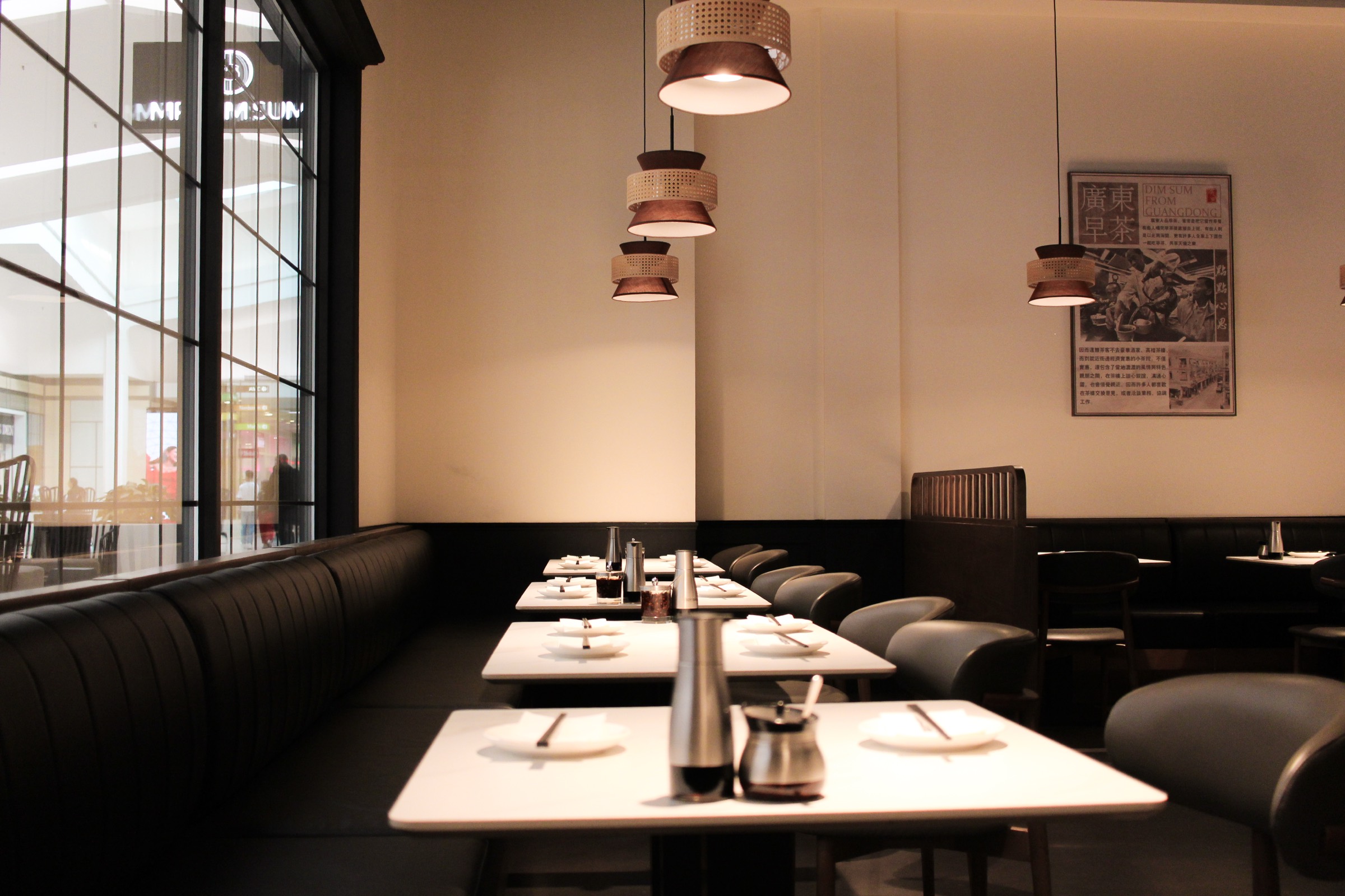 The dining room at Mr. Dim Sum, with rattan pendant lights and a Dim Sum from Guangdong poster